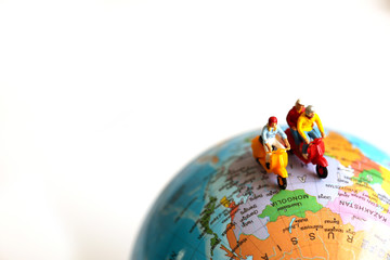 Group of traveler miniature people figures ride motorcycle / scooter to world map.