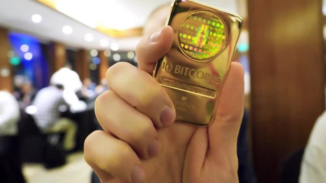 Man holding the gold bullion with Bitcoin symbol on it. Concept of Cryptocurrency physical bitcoin with gold bar and sunburst effect. BTC gold.