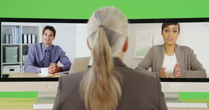 A older office executive chats with two of her employees on green screen. On green screen to be keyed or composited. 