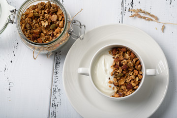 Healthy breakfast: Greek yogurt with homemade granola in a white bowl and jar with granola
