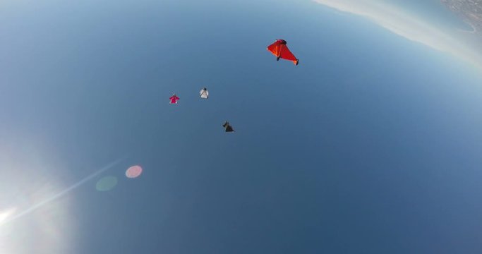 A base jumper in a wingsuit leaping off a from a rocky cliff, gliding down over a green landscape
