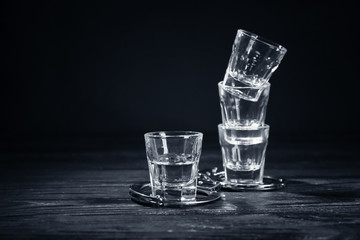 Glasses with handcuffs on dark background. Alcohol dependence concept