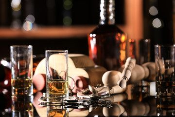 Composition of glassware and toy car with handcuffs on table in bar. Don't drink and drive concept