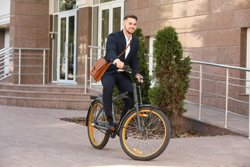 Young handsome businessman riding bicycle outdoors