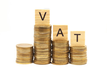 Word Vat Concept on wooden block over on stacked coins.