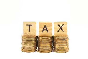 Word Tax Concept on wooden block over on stacked coins