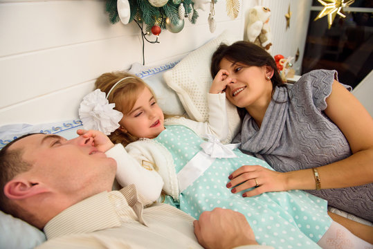 Mother, father and baby having fun in bedroom. People relaxing at home. Winter holiday Xmas and New Year concept