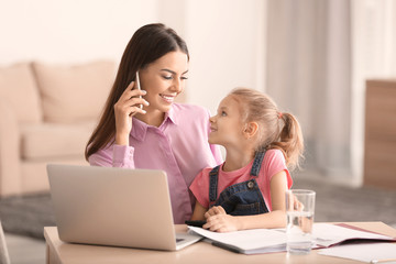 Fototapeta na wymiar Busy young woman with daughter in home office