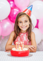 Happy girl in party hat with birthday cake