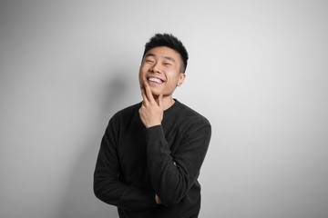 Portrait of young Asian man on light background