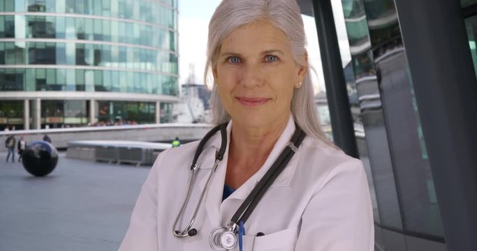 Casual portrait of happy mature woman surgeon outside hospital