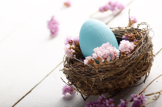 Rustic style painted easter egg in the nest on white table