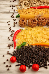 Spaghetti, pasta in the form of nests with red hot bitter pepper and tomatoes on a white wooden background
