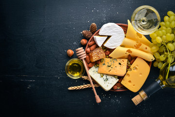 Assortment of cheeses, a bottle of wine, honey, nuts and spices, on a wooden table. Top view. Free space for text.