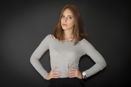 Portrait of a red hair girl, 18Y, on black background. Hands at hips. 