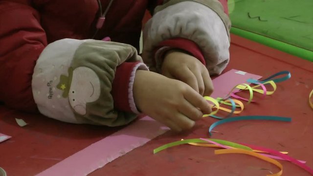 A little girl is learning to make paper decorations 