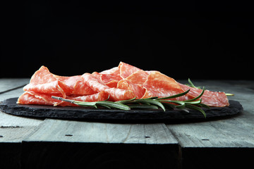 Stone cutting board with sliced salami on it