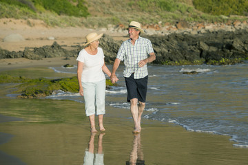 lovely senior mature couple on their 60s or 70s retired walking happy and relaxed on beach sea shore in romantic aging together