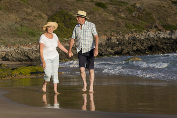 lovely senior mature couple on their 60s or 70s retired walking happy and relaxed on beach sea shore in romantic aging together