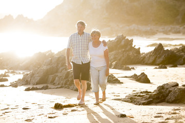 lovely senior mature couple on their 60s or 70s retired walking happy and relaxed on beach sea...