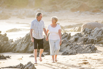 lovely senior mature couple on their 60s or 70s retired walking happy and relaxed on beach sea shore in romantic aging together