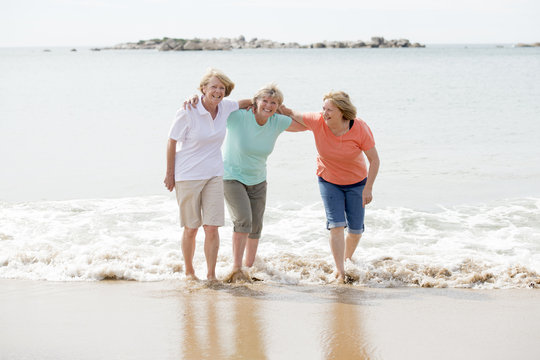 Group Of Three Senior Mature Retired Women On Their 60s Having Fun Enjoying Together Happy Walking On The Beach Smiling Playful