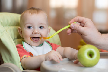 Baby eating healthy food with father help at home