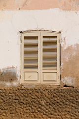 A run down rustic brown and cream shutters on windows in Santa Maria, Sal, Cabo Verde, Africa.