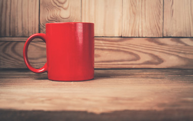 Red coffee mug on a wood background.