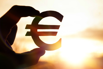 euro symbol in hand on sunset background