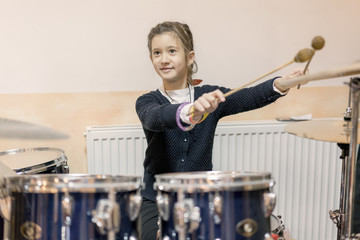 Happy girl in music therapy by playing drum kit on music room