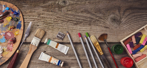 Artistic equipment:  watercolor, pastel, paintbrushes, tubes of paint, Palette with oil paints and pencils on wooden table. Space for text.
