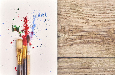 Paintbrushes with painted abstract background over wood board