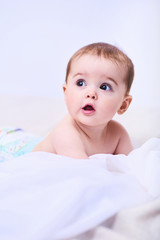 Portrait of a smiling crawling baby on the bed in her room. Space for text