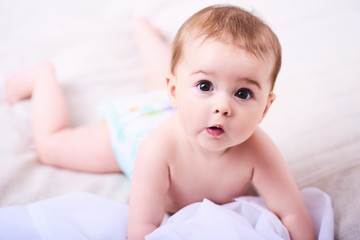 Portrait of a smiling crawling baby on the bed in her room. Space for text