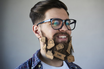 Smaling Handsome man in glasses with stickers on beard on gray background