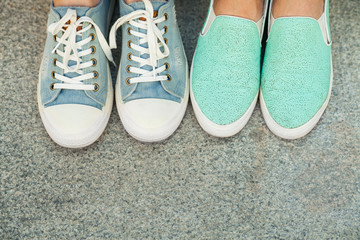 Close up view of two pairs teen's feet feet in blue sneakers