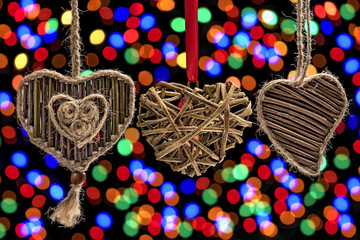 Three hearts made from natural materials (wood twigs) against the background of a colorful bokeh. - 185014991