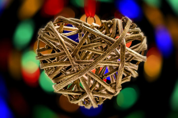 One heart made of natural materials (woody branches) against the background of a colorful bokeh.