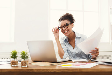 Happy business woman reading document at office desktop