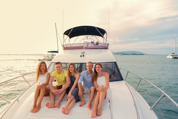 Group of happy people on luxury white yacht at sunset. Luxury yacht cruise concept.