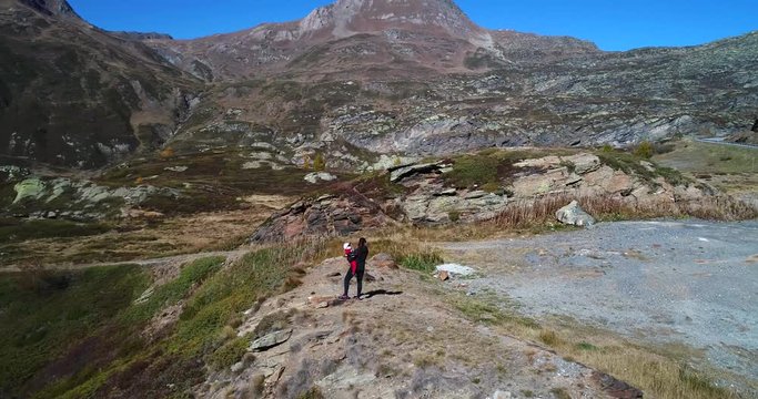 Woman and child, Cinema 4k aerial view around a mother and a kid, standing on a mountain ledge, on a sunny fall day, on simplon pass, in wallis, of the alps in Switzerland