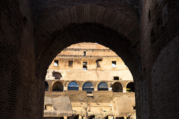 Part of the wall of Colosseum (Coliseum) in Rome, Italy at sunset view through the arch