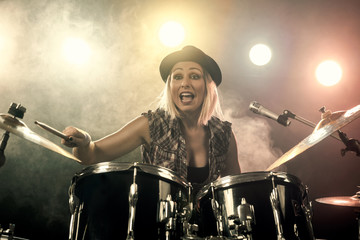 portrait of emotional woman playing drums in studio, drummer rock concept