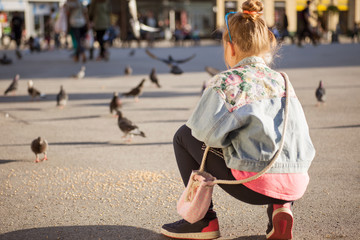 Adorable little girl feeding pigeons outdoors