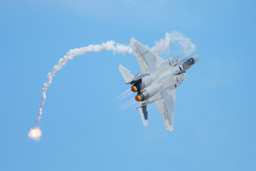 Close view of an F-15 Eagle in a tight turn, with afterburners on and flares deployed