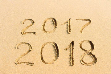  New Year concept - 2017 and 2018 handwritten on the sandy beach