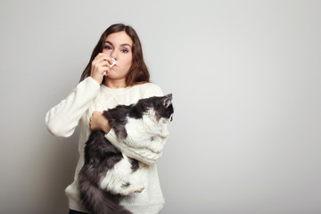 Young woman with allergy holding cat on grey background
