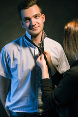 Man letting a woman to knot a tie. Couple family relationship. Love care help support concept