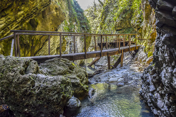 Fototapeta premium wooden bridge over the blue river in the jungle rock cliff